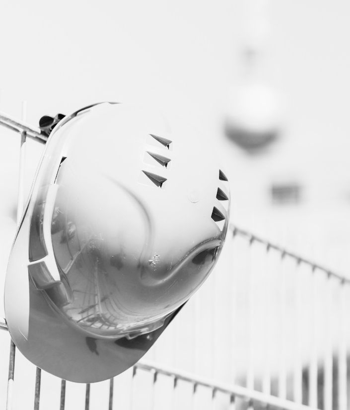 Schutzhelm hängt an einem Bauzaun – persönliche Schutzausrüstung als Symbol für Arbeitssicherheit auf der Baustelle